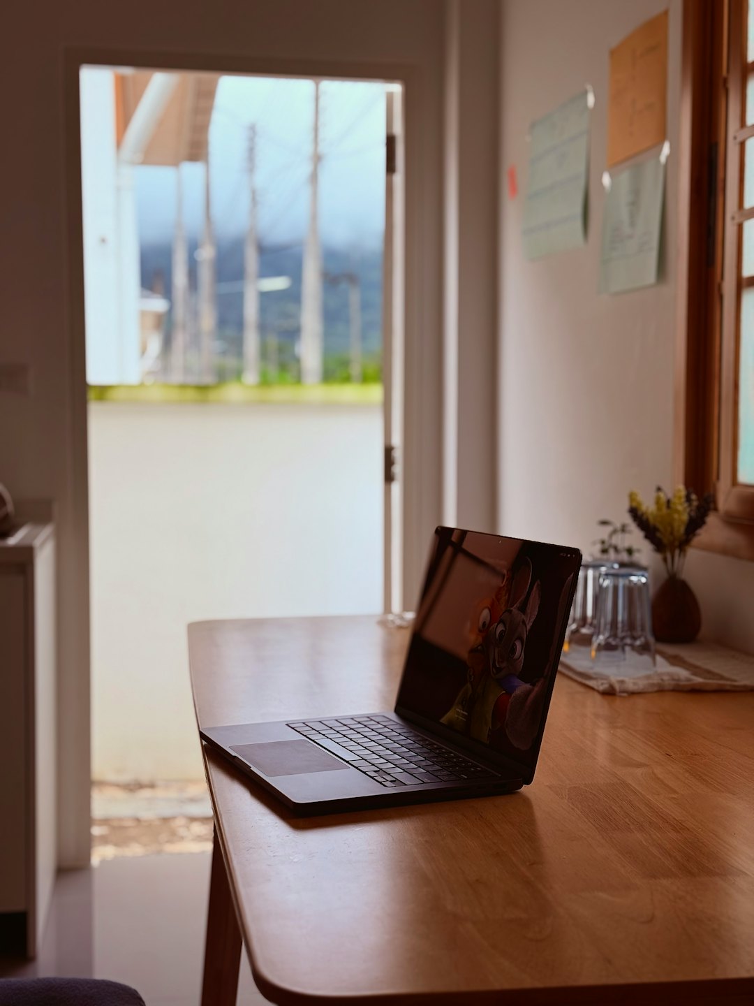 Laptop open showing cartoon characters on wooden table.