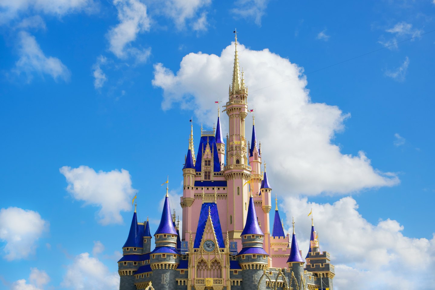 Pink fairytale castle with blue roofs and gold spires.