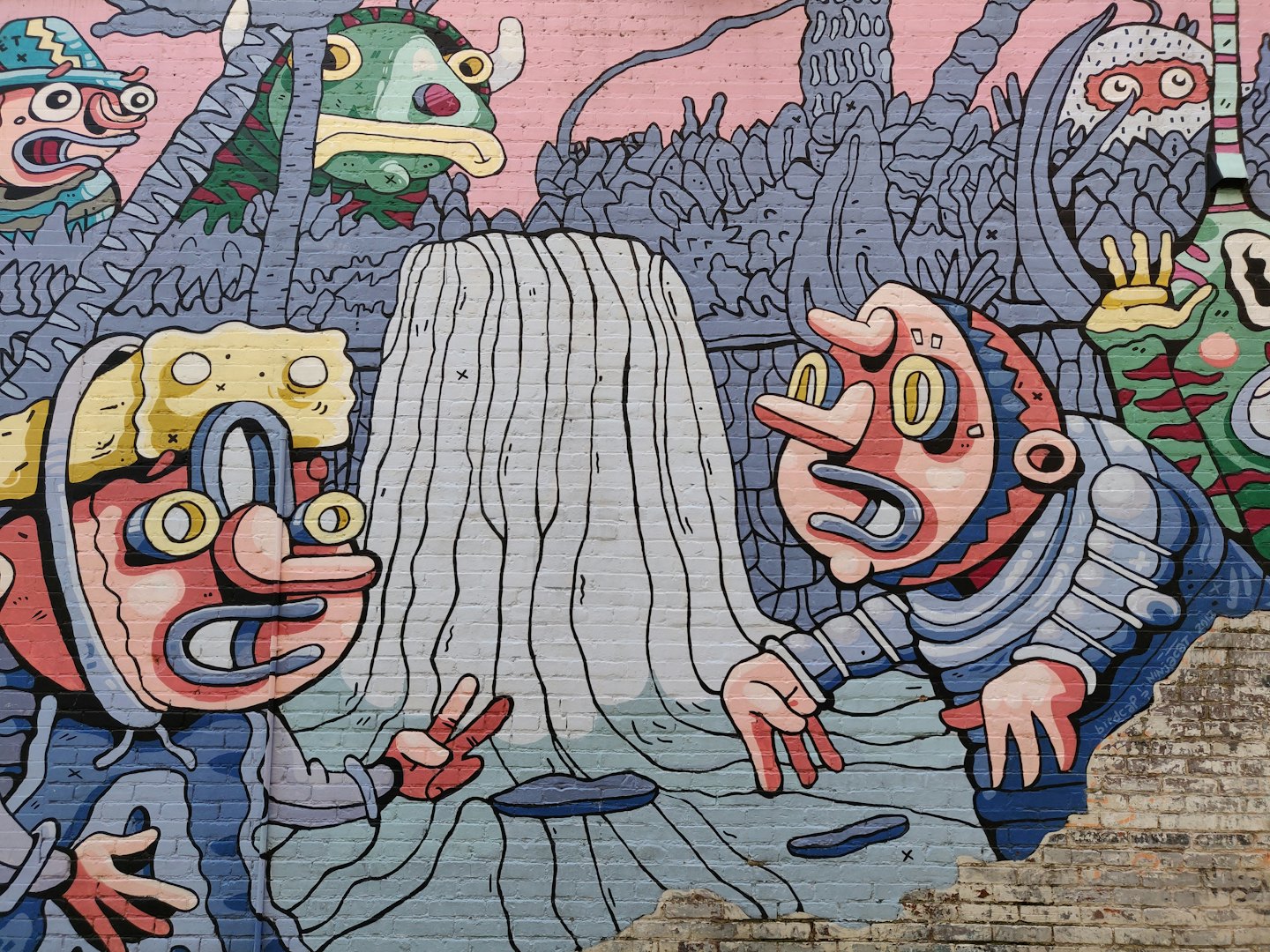 Colorful cartoon characters painted on an outdoor brick wall.